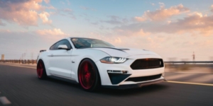 ford mustang driving fast under a pink sky